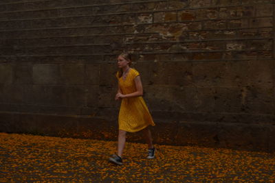 Portrait of teenage girl standing against brick wall