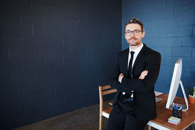 Portrait of a smiling young man sitting on wall