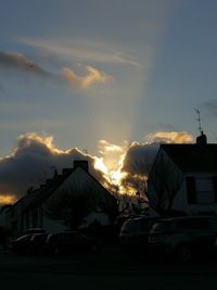 Cars on house in city against sky during sunset