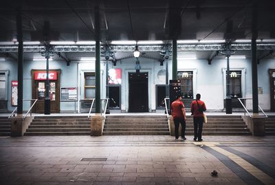 Rear view of people walking on illuminated railroad station