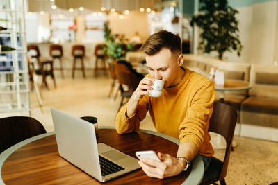 Young woman using laptop in coffee cup