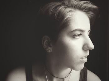 Close-up of thoughtful young woman looking away against black background