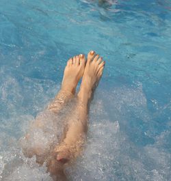 Low section of person relaxing in swimming pool