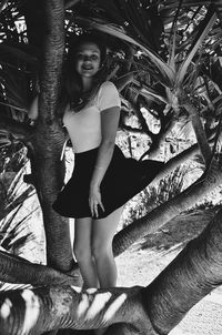 Portrait of smiling young woman standing against tree