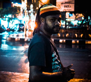 Portrait of young man standing on street at night