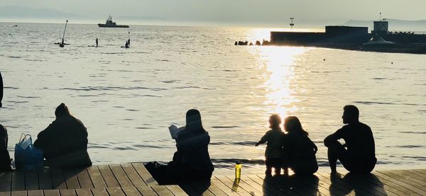 Silhouette people looking at sea against sky