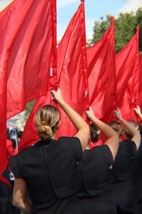 Rear view of females holding red flags