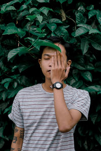 Portrait of young man standing against plants