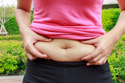 Midsection of woman holding belly standing outdoors