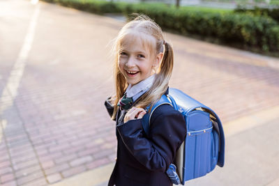 Back to school. little girl with blue backpack from elementary school outdoor