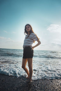 Full length of woman standing on beach against sky