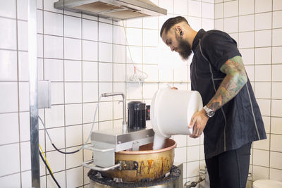 Male worker pouring sugar in machine at candy store