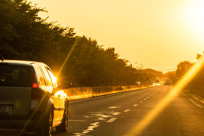 Cars on street against sky during sunset