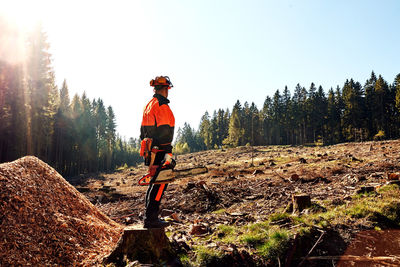 Professional lumberjack with protective workwear and chainsaw working in a forest