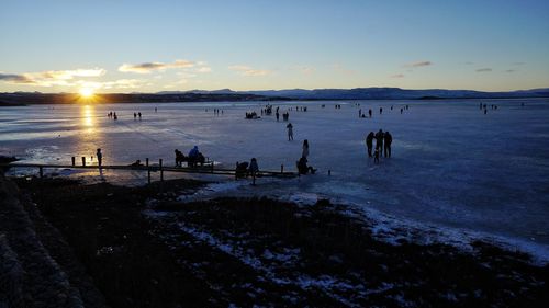 Group of people on beach during sunset