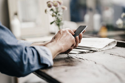 Midsection of man using mobile phone on table