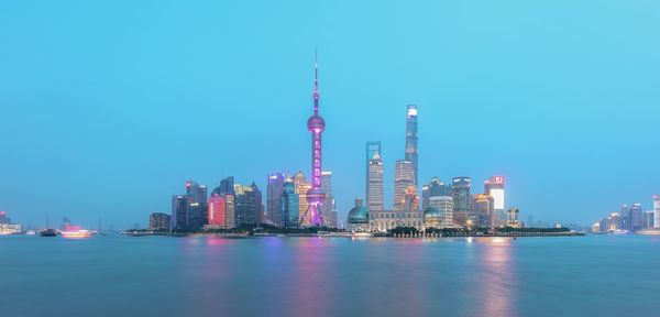 Illuminated buildings in city against clear sky