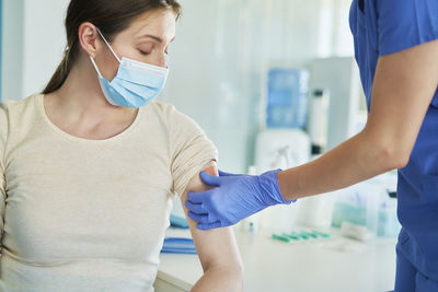 Midsection of doctor vaccinating patient at hospital