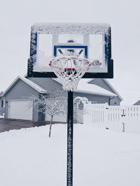 Snow covered basketball hoop against sky