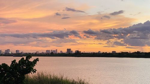 Scenic view of sea and buildings against sky during sunset