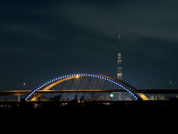 Illuminated bridge against sky at night