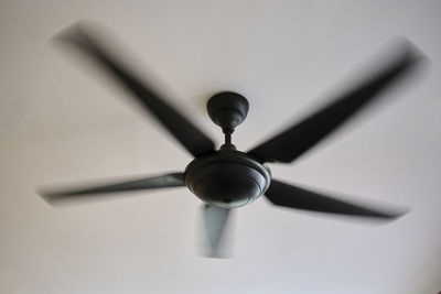Low angle view of electric fan hanging on ceiling at home