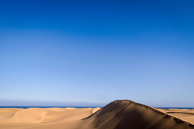 Scenic view of desert against clear blue sky