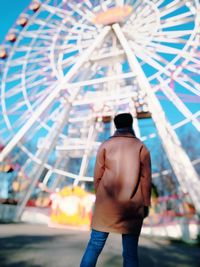 Rear view of shirtless man standing at amusement park