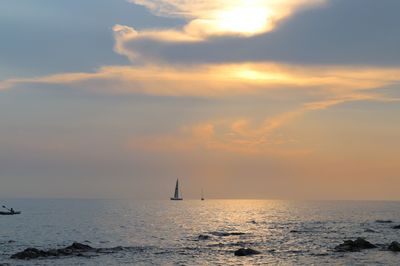 Boats sailing in sea against sky during sunset