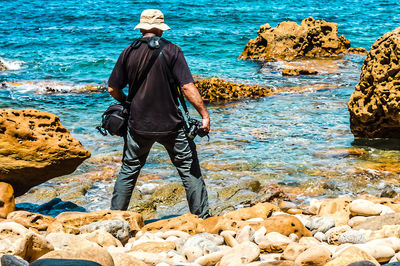 Rear view of man standing on rock at beach