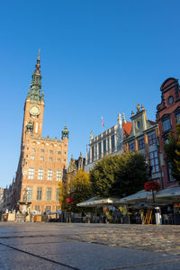Clock tower amidst buildings in city against blue sky