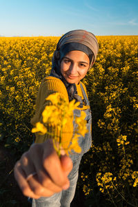 Midsection of woman with yellow flowers on field