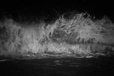 Water splashing in sea against sky at night