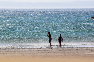 Siblings on beach against sky