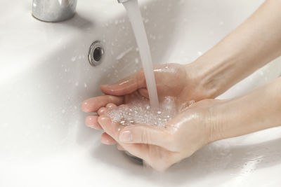 Midsection of woman touching water in bathroom