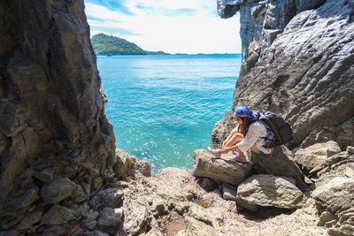 People on rock by sea against sky