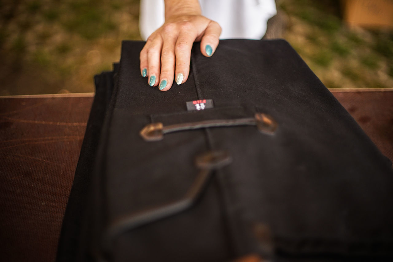 human hand, hand, human body part, real people, one person, selective focus, midsection, day, lifestyles, standing, holding, publication, body part, religion, book, black color, high angle view, outdoors, finger