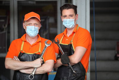 Portrait of male workers wearing face masks standing in garage