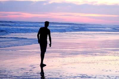 Solitary man on beach at sunrise