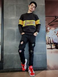 Full length portrait of man standing against wall