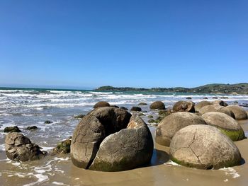 Rocks on sea shore against clear sky