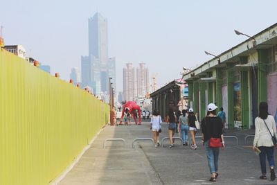 People walking in city against clear sky