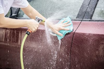 Cropped hands of man washing car