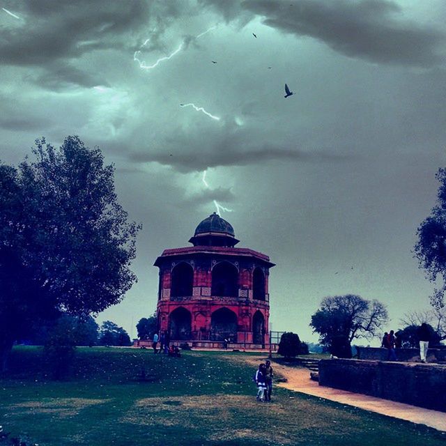 sky, building exterior, architecture, built structure, cloud - sky, tree, cloudy, flying, bird, animal themes, church, place of worship, religion, cloud, grass, spirituality, outdoors, incidental people, facade