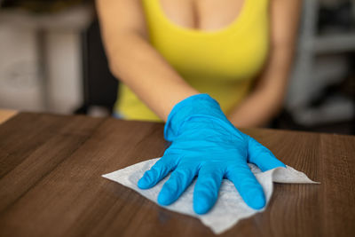 Midsection of woman holding blue table at home