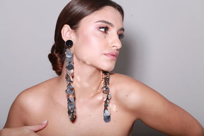 High end fashion  head shot of brunette model wearing long shiny earrings, professional make up