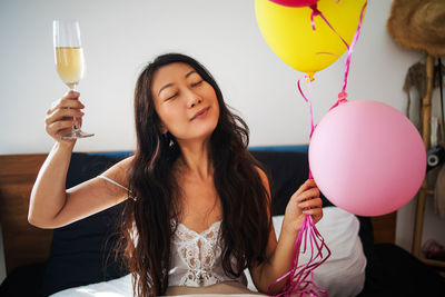 Young asian woman holding balloons on bed