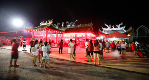 Crowd at illuminated amusement park against sky at night