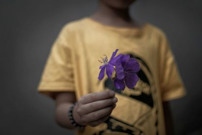 Midsection of boy holding purple flower