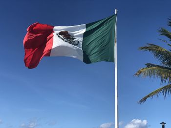 Low angle view of flag against blue sky